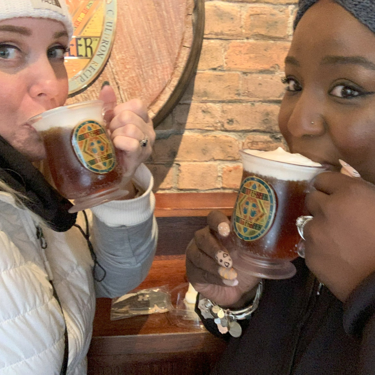 Close up selfie of Dana and Kernika drinking full mugs of butterbeer at Harry Potter Store in NYC